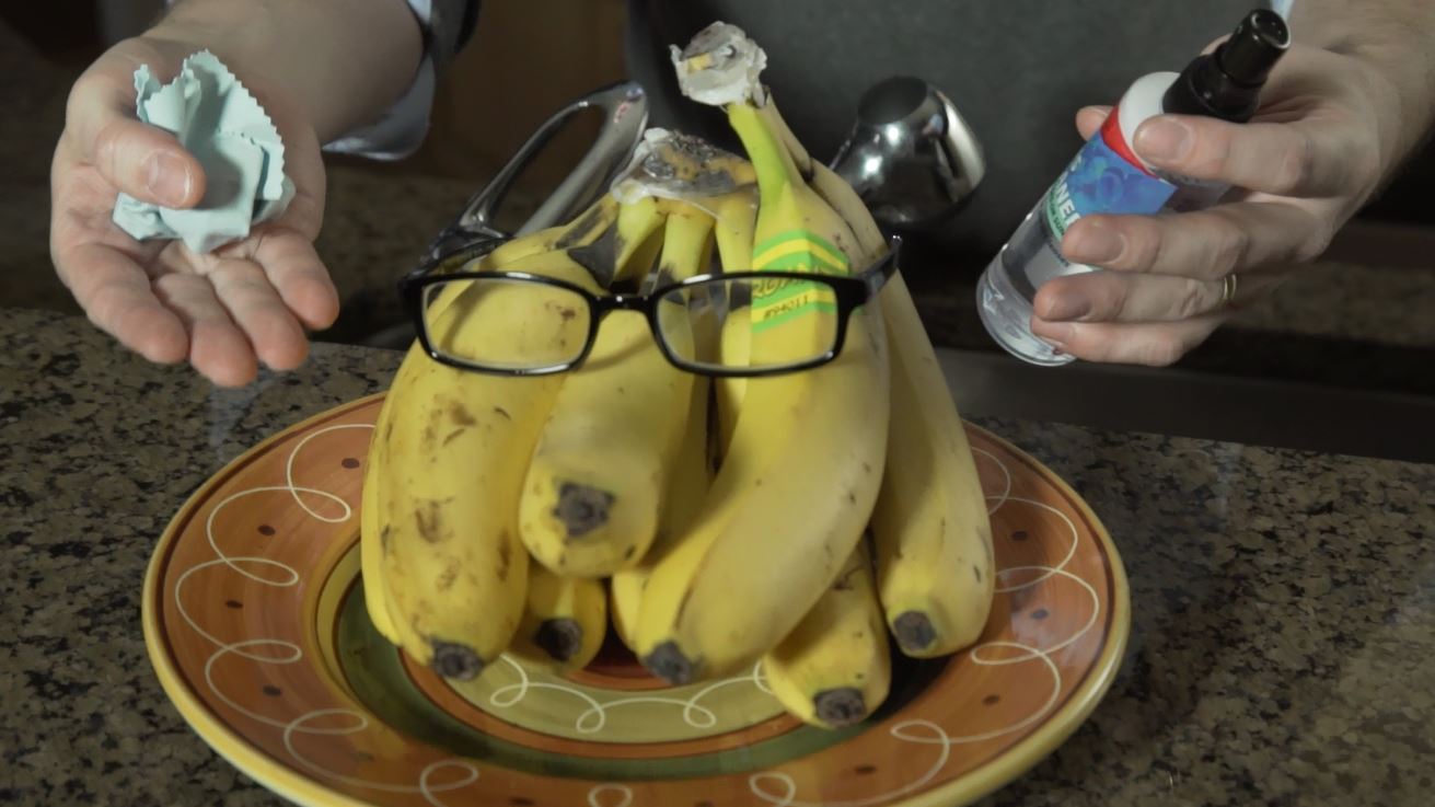 bananas wearing glasses, with glass cleaner and cloth held nearby
