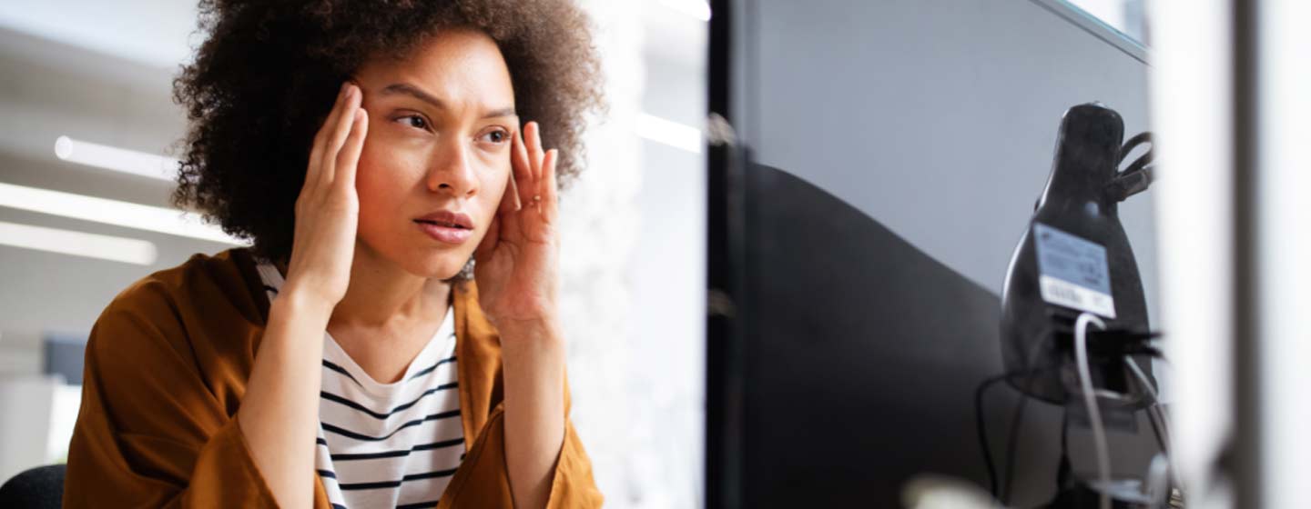 Overworked and frustrated young woman in front of computer in office