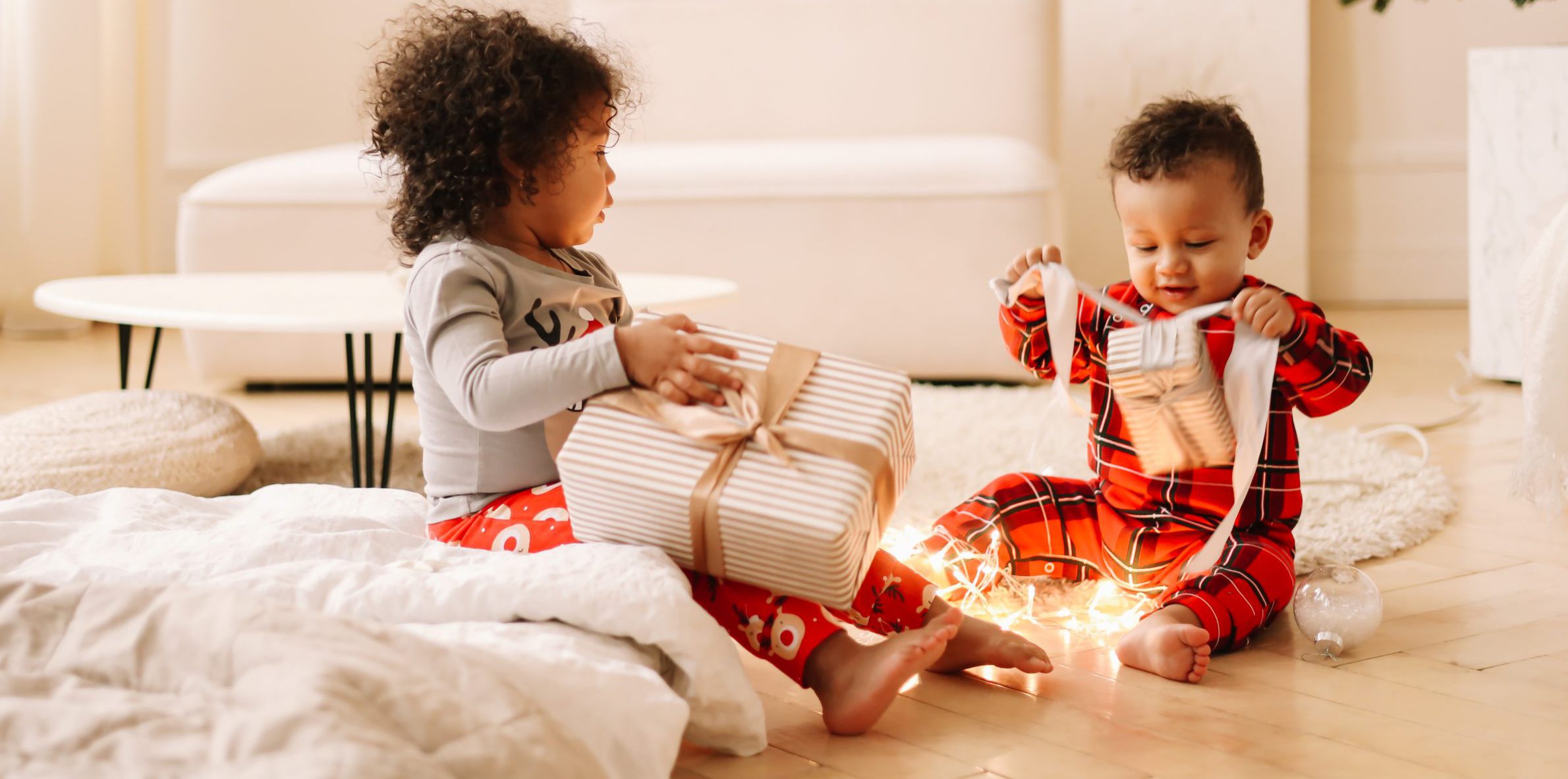 children wearing Christmas pajamas opening gifts