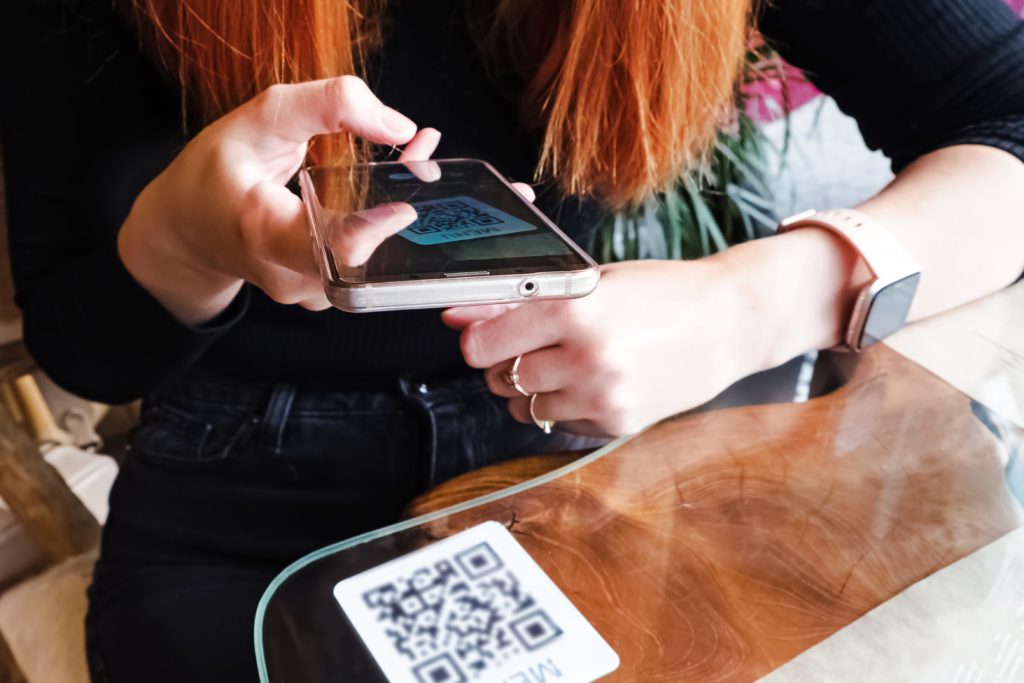 Woman scanning the barcode qr code in restaurant or cafe